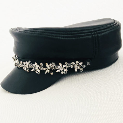 La Casquette des Saintes Ida Degliame est un modèle en cuir noir avec un bijou en strass